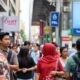 Busy street scene in Southeast Asia with people walking and shopping.
