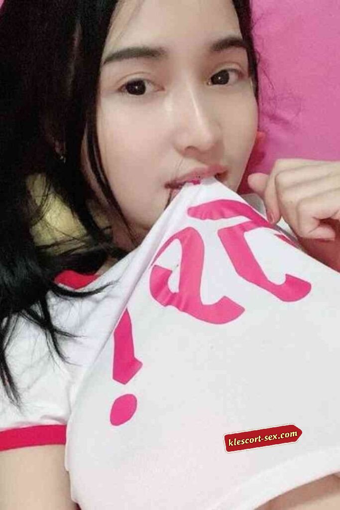 Asian woman playfully biting white shirt with pink lettering.