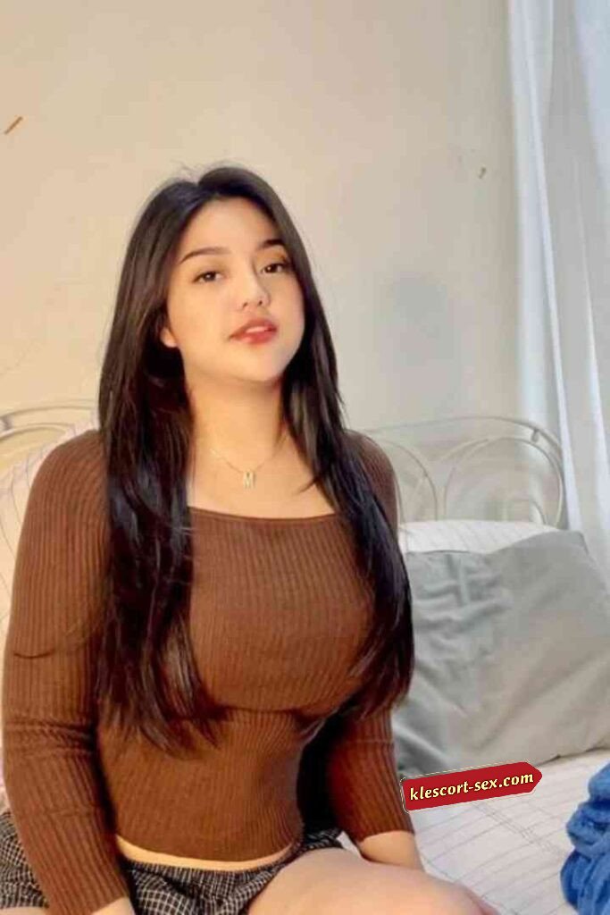 Beautiful Asian woman with long dark hair, brown top, and necklace posing indoors.