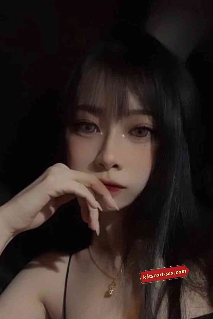 Young Asian woman with dark hair and bangs, looking at the camera with a thoughtful expression.