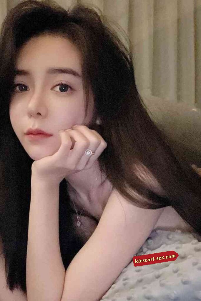 Beautiful Asian woman with long dark hair resting her chin on her hand, wearing a ring and necklace.