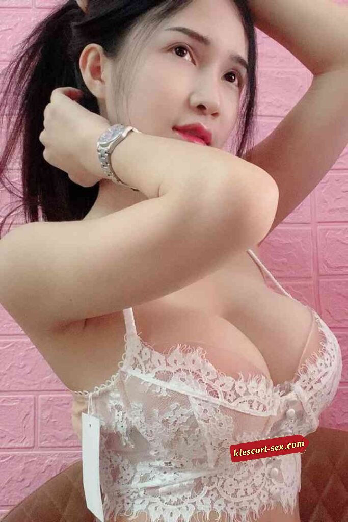 Asian woman in lace bra with watch looking up.