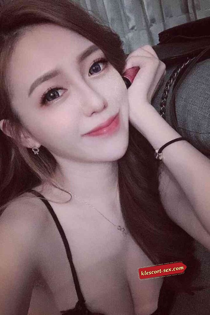 Attractive Asian woman with long brown hair smiling, wearing a black top.