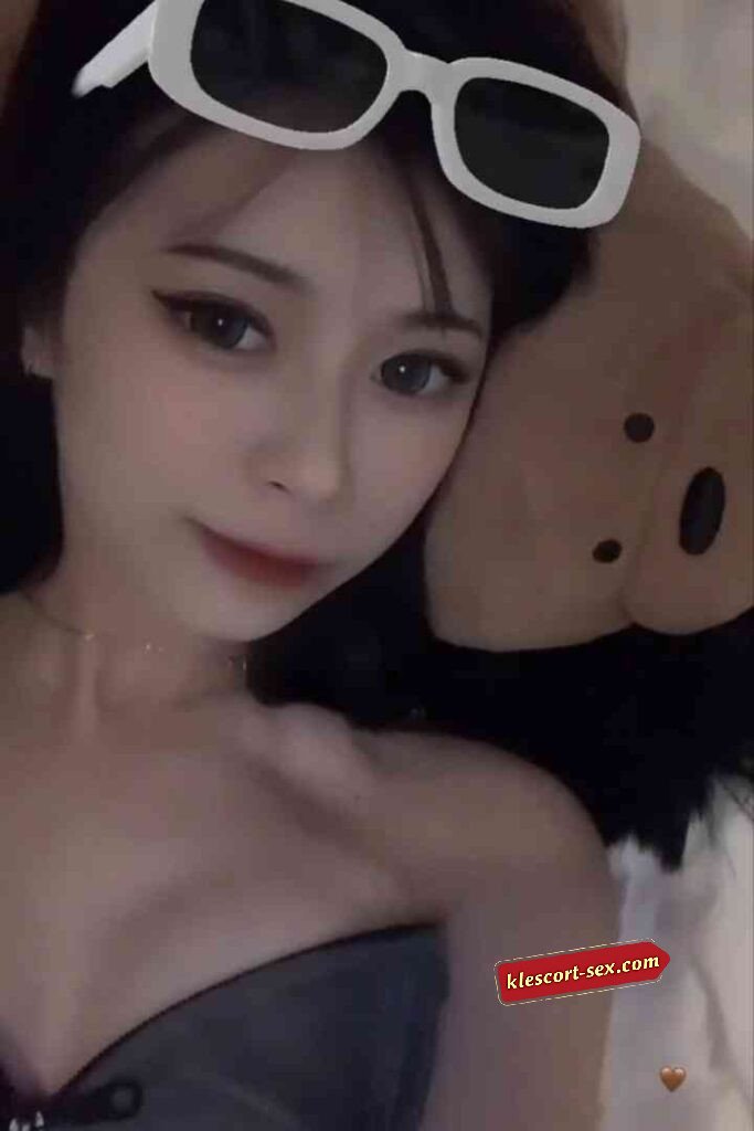 Asian woman with sunglasses on head, lying down with stuffed animal.