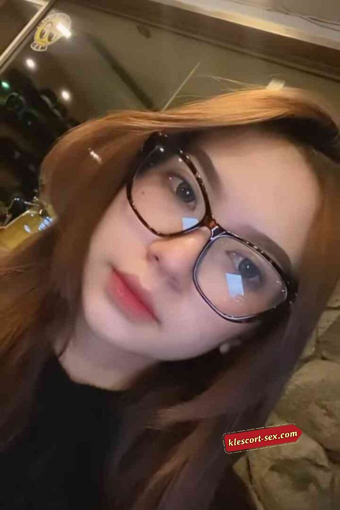 Woman with auburn hair wearing glasses. Portrait of a young lady.