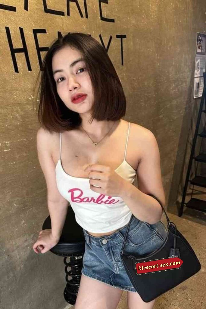 Young woman in Barbie top and denim shorts with Prada bag.