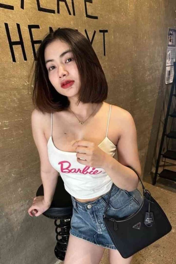 Woman in Barbie top, denim shorts, and black Prada bag.