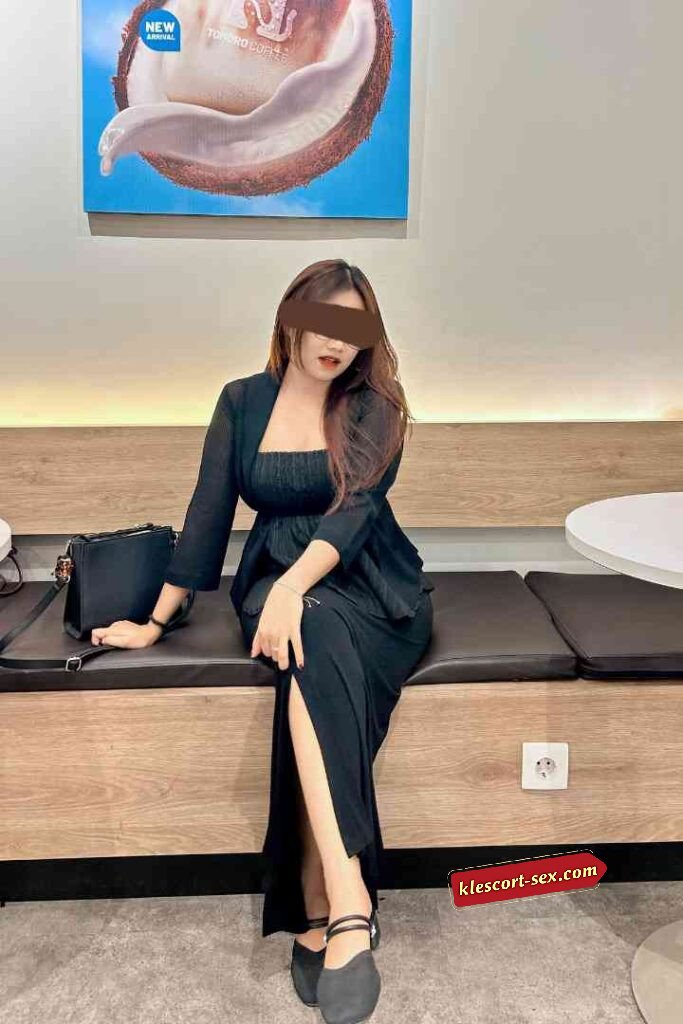 Woman in black dress sitting on bench in cafe.