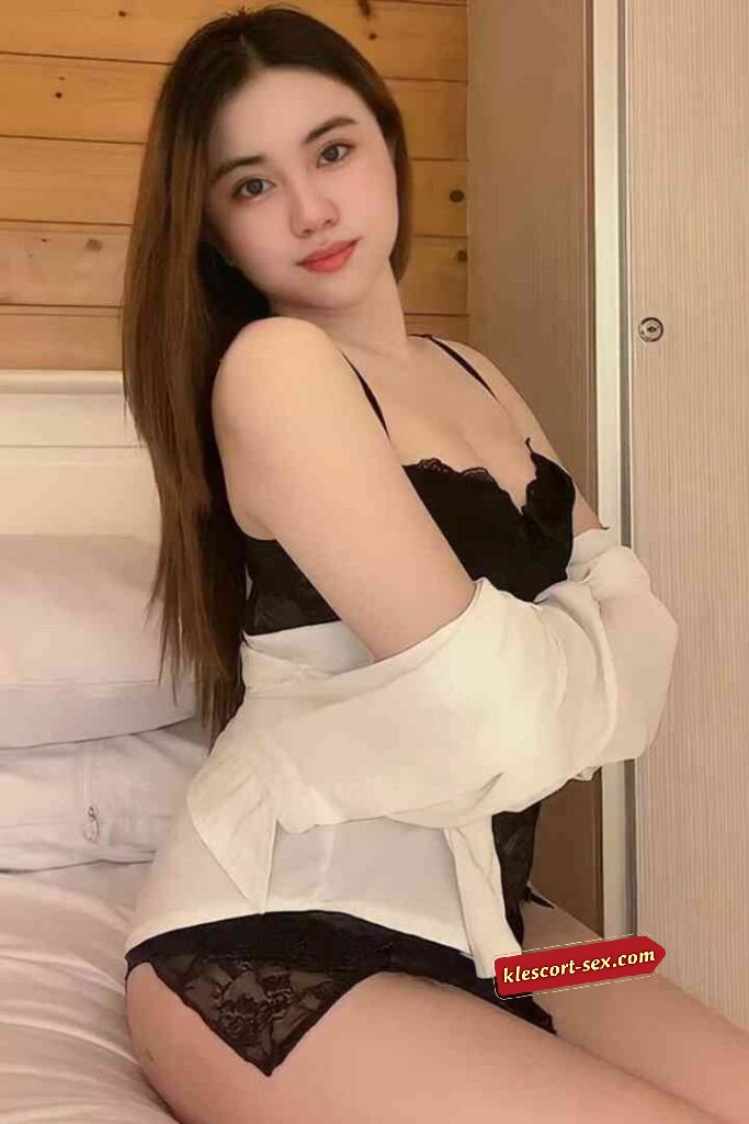 Woman in black lingerie and white shirt posing on bed.