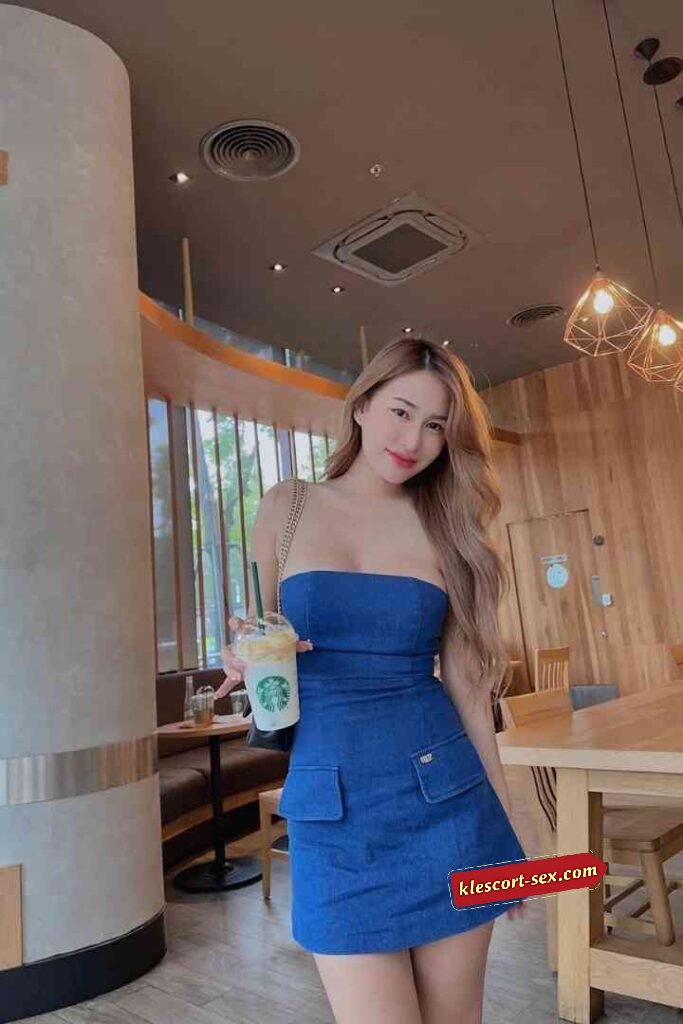 Woman in blue dress holding Starbucks drink in cafe.