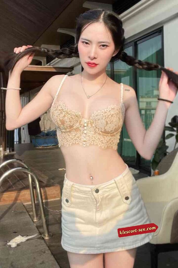 Woman with braided pigtails in lace bra top and mini skirt.