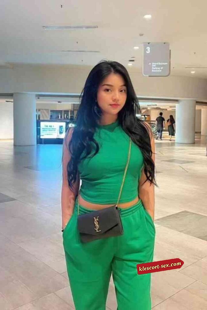Young woman in green crop top and sweats with black YSL bag.