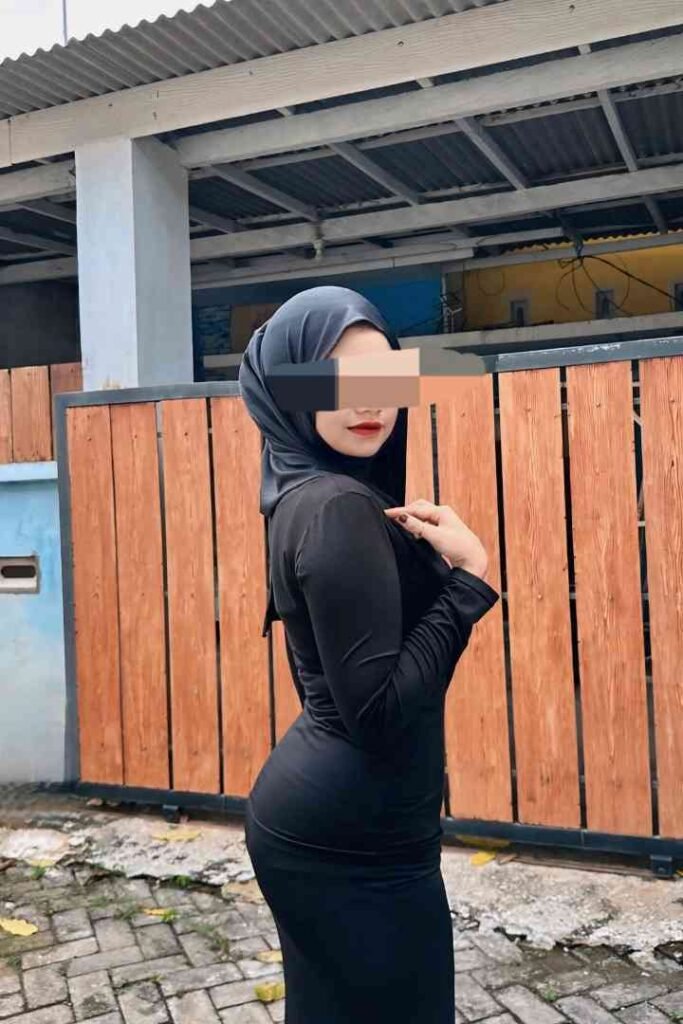 Woman in hijab wearing black dress outdoors.