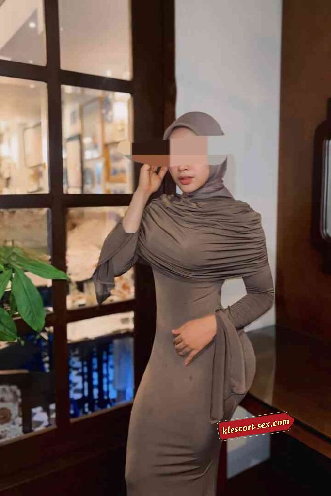 Woman in stylish hijab and dress posing indoors.