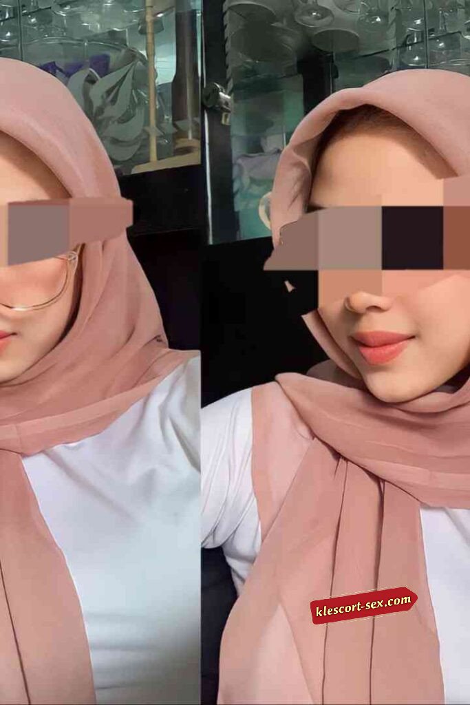 Woman in hijab wearing glasses and white top.