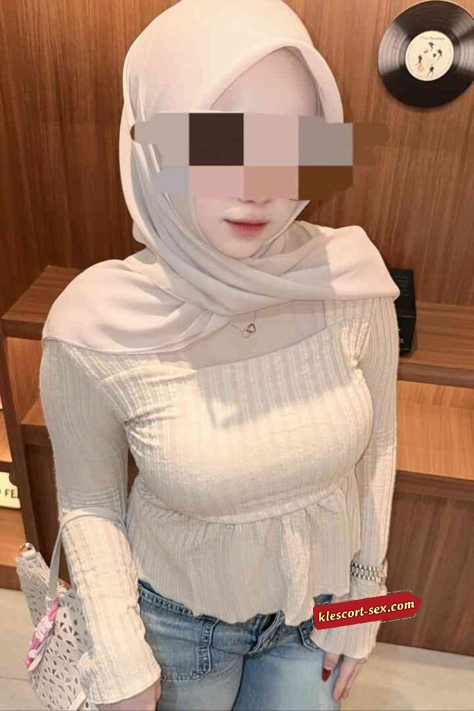 Woman in hijab and light-colored top with peplum waist and jeans.