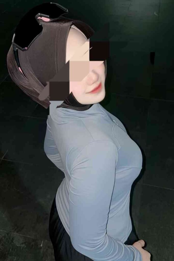 Woman in hijab and sports gear, side view. Black and gray athletic attire.