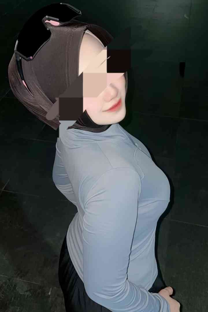 Woman in hijab and sports gear, side view. Black and gray athletic attire.