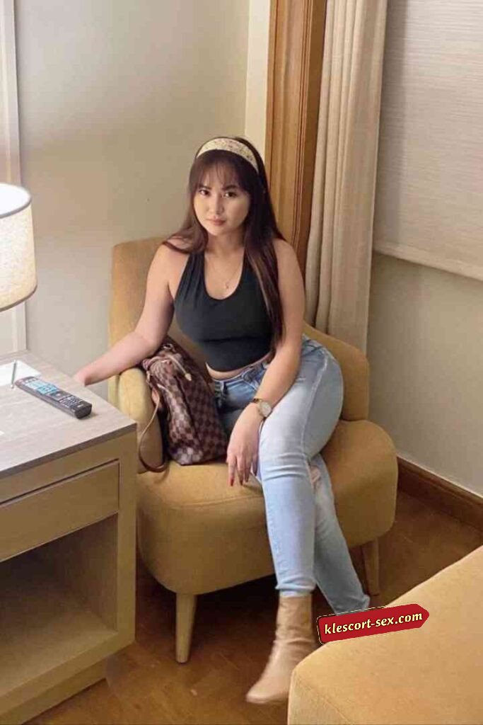 Woman in jeans and black top sitting in chair.