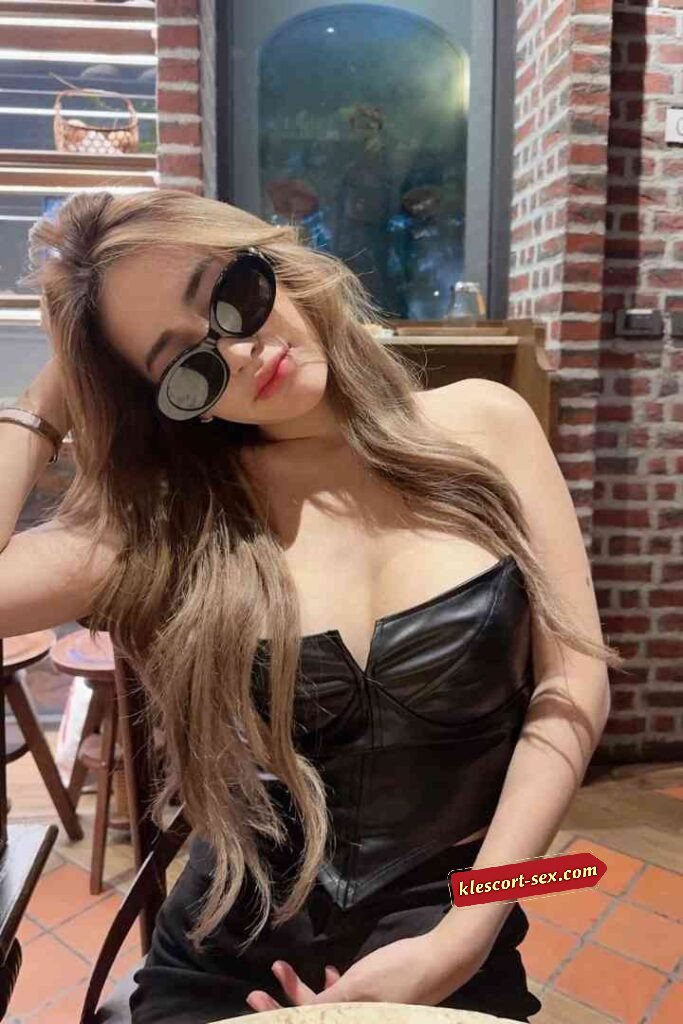 Stylish woman in leather top and sunglasses posing indoors.