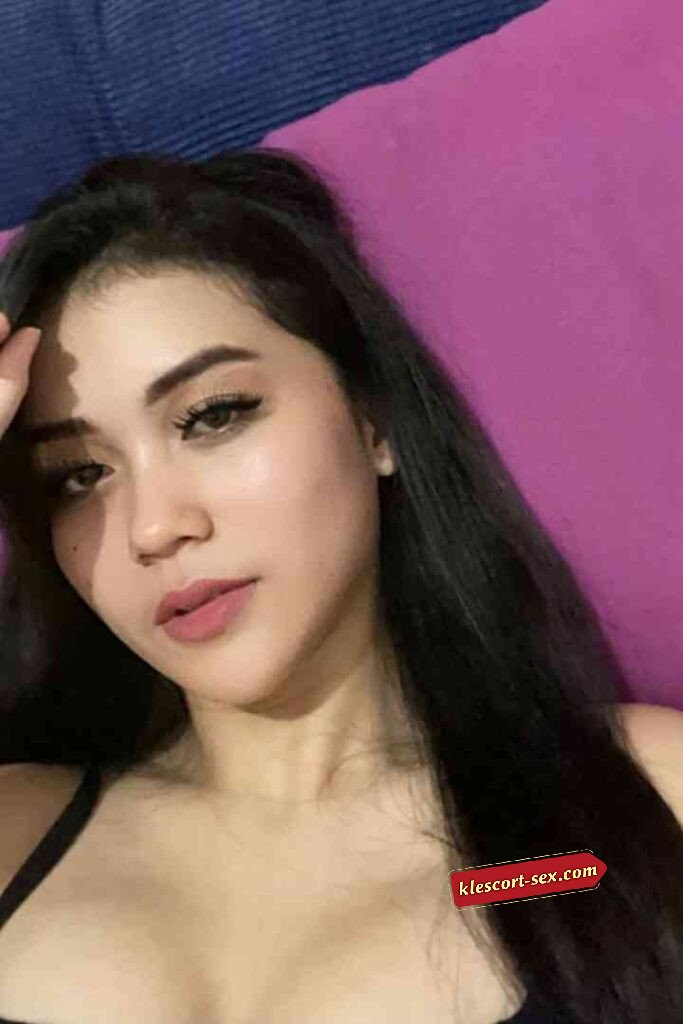 Portrait of a woman with long dark hair and pink lipstick looking at the camera.