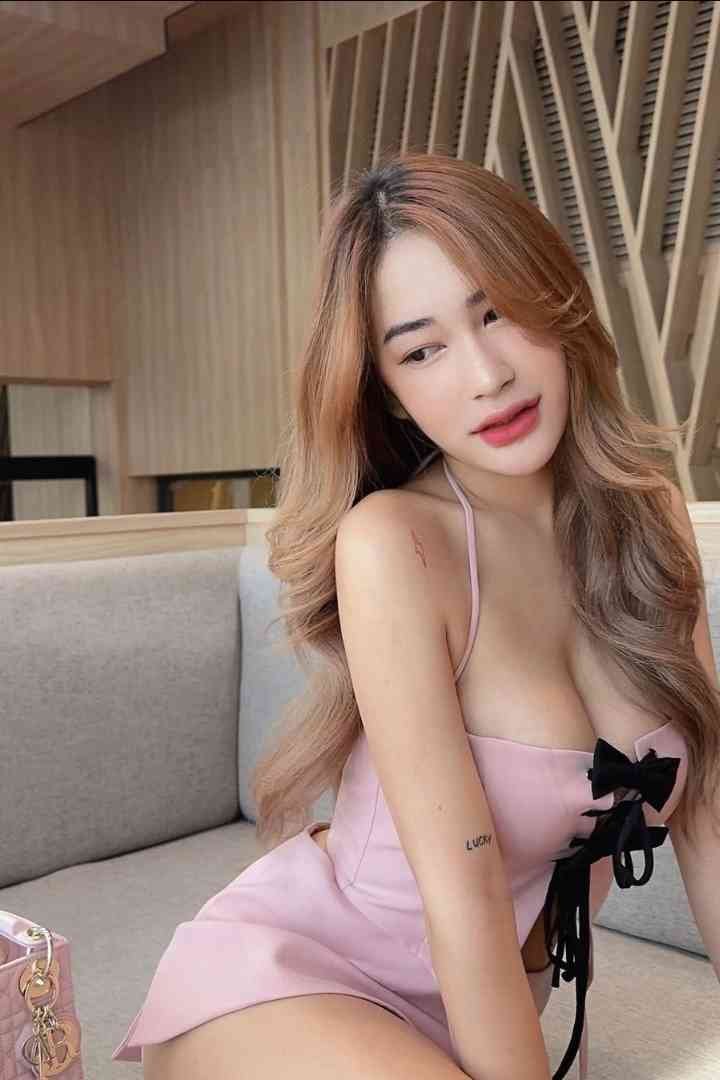 Attractive woman in pink dress with bow detail sitting on couch.