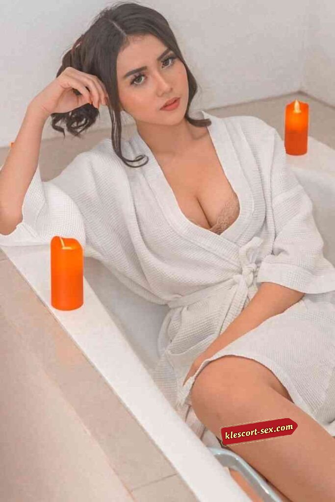 Woman in robe relaxing in tub with candles. Spa day at home.