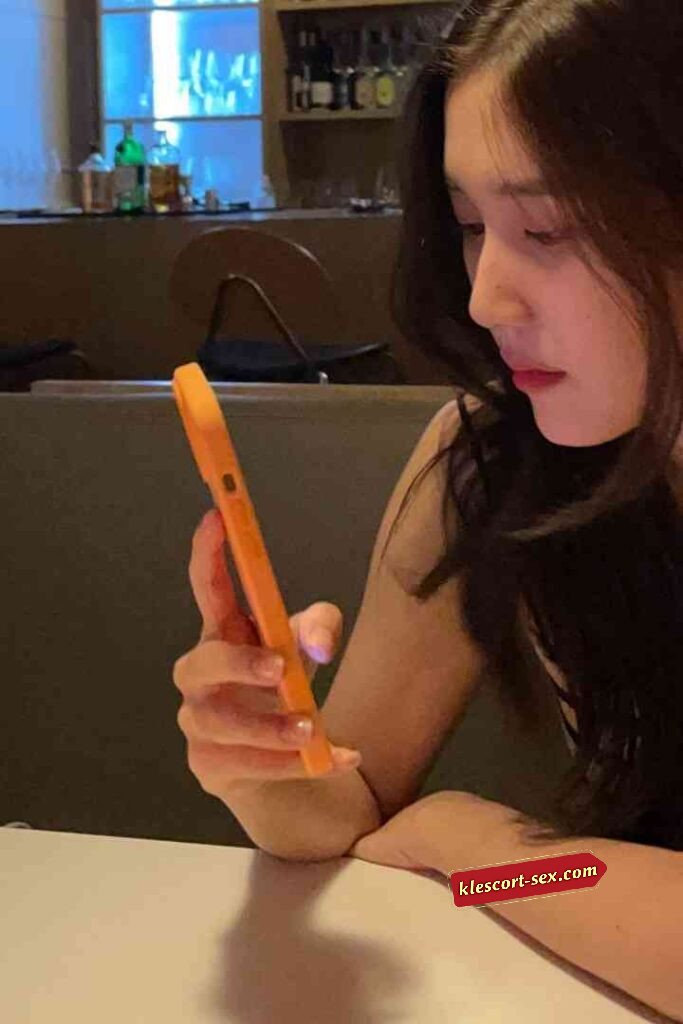 Woman using orange phone at table in restaurant setting.