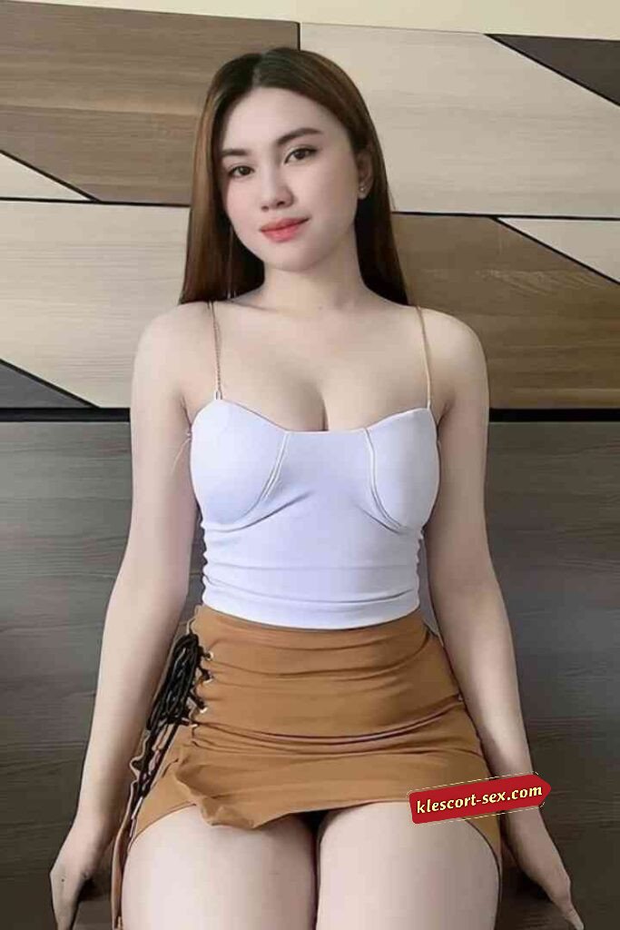 Attractive woman in white top and brown mini skirt posing indoors.