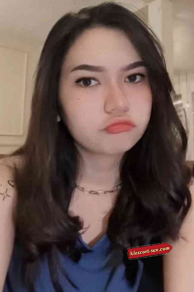 Portrait of a young woman with dark hair and a pouty expression.