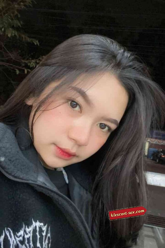 Portrait of a young woman with dark hair and red lipstick, wearing a black jacket.