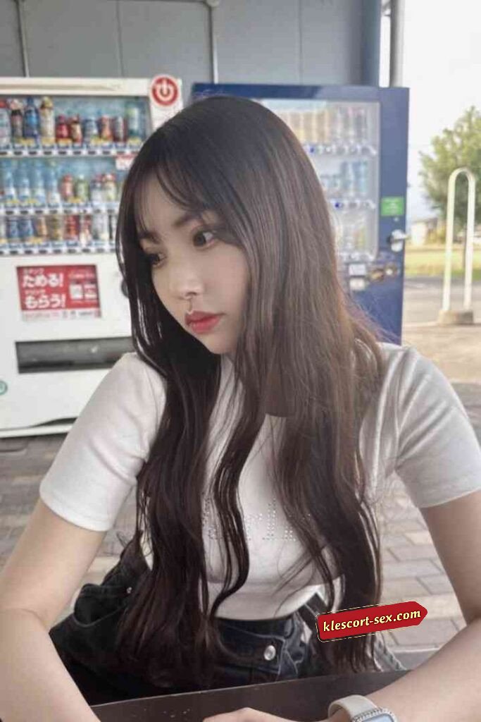 Young woman with long dark hair in front of a vending machine.
