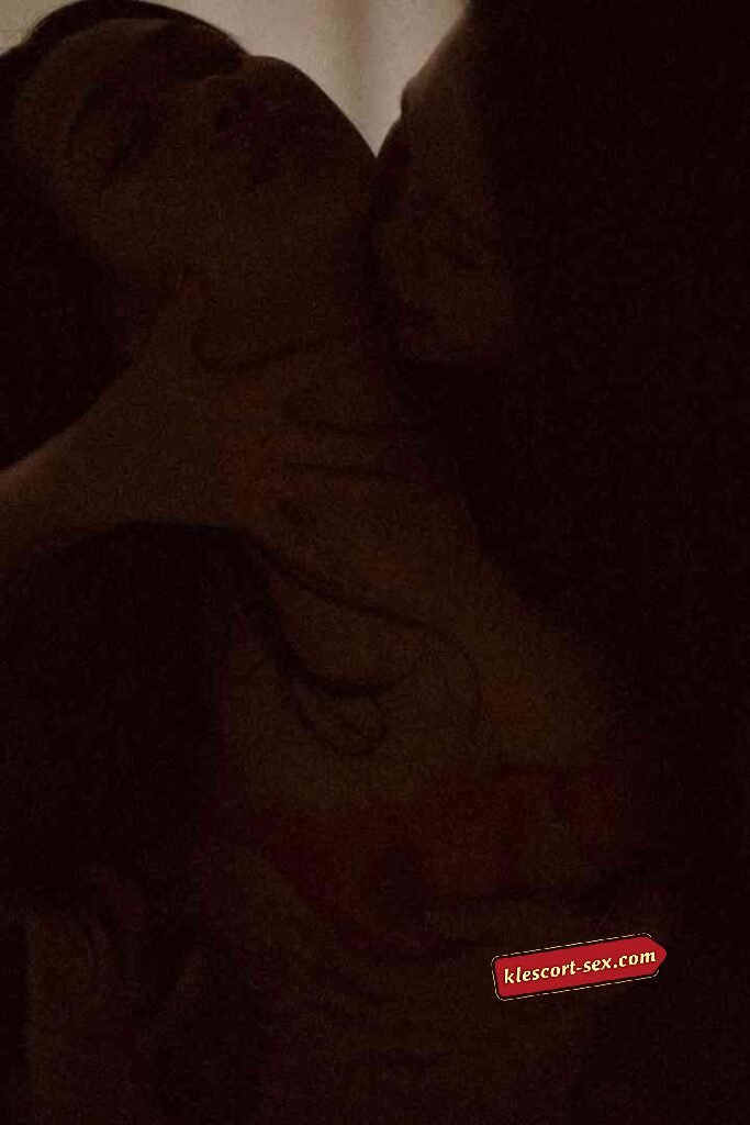 KL Escort Girl Couple embracing intimately in dim lighting, with a tattoo visible on the woman's chest. Sex Service Malaysia