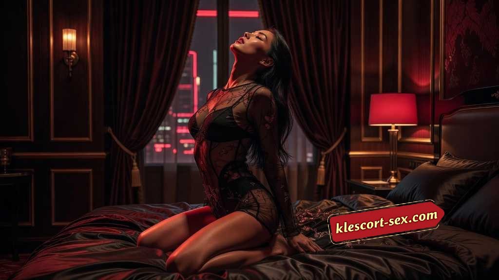 KL Escort Girl Woman in sheer lingerie posing on a bed in a dimly lit, luxurious room with city view. Sex Service Malaysia