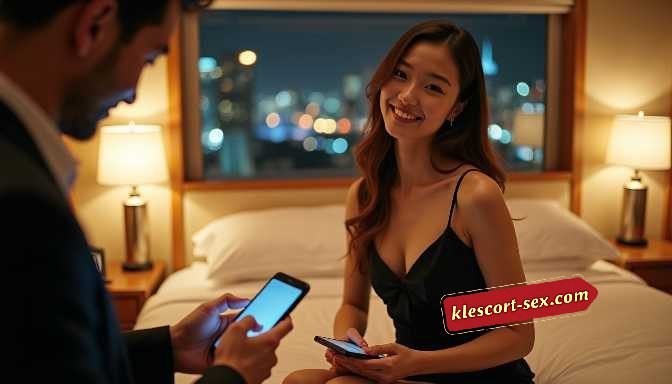 KL Escort Girl Smiling woman looks at phone as man in foreground also uses his phone in a dimly lit room. Sex Service Malaysia